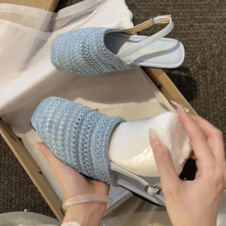 Blue knit slippers being put on a white shoe with a hand adjusting the fit.