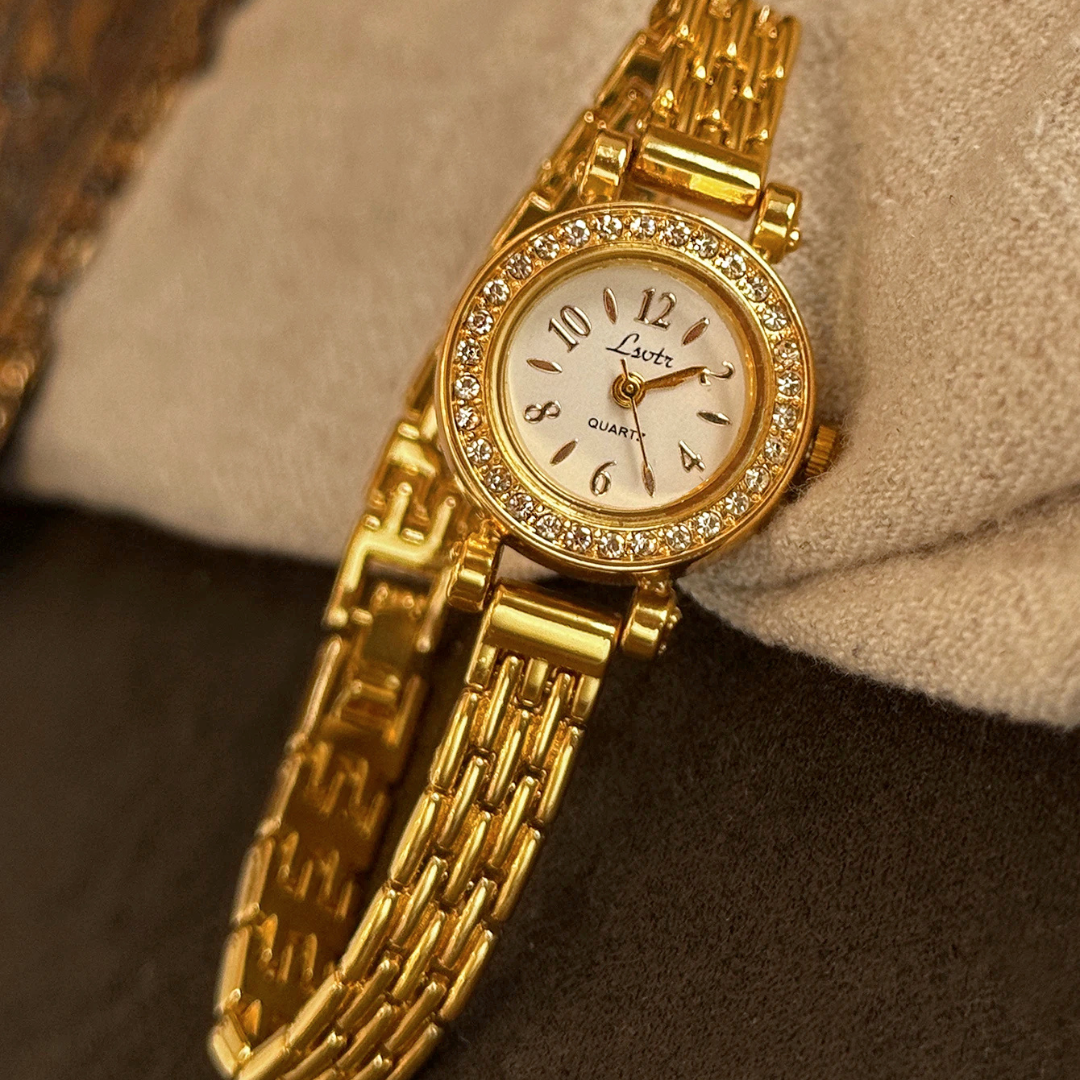 Gold wristwatch with diamond accents on a textured surface