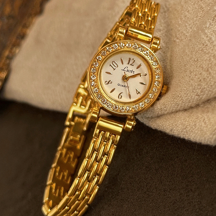 Gold wristwatch with diamond accents on a textured surface