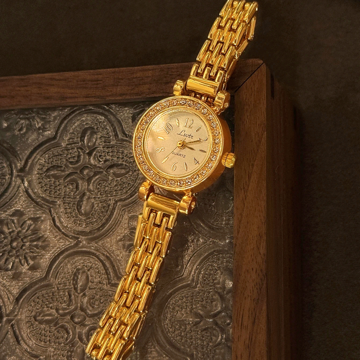 Gold wristwatch with intricate design on a textured surface