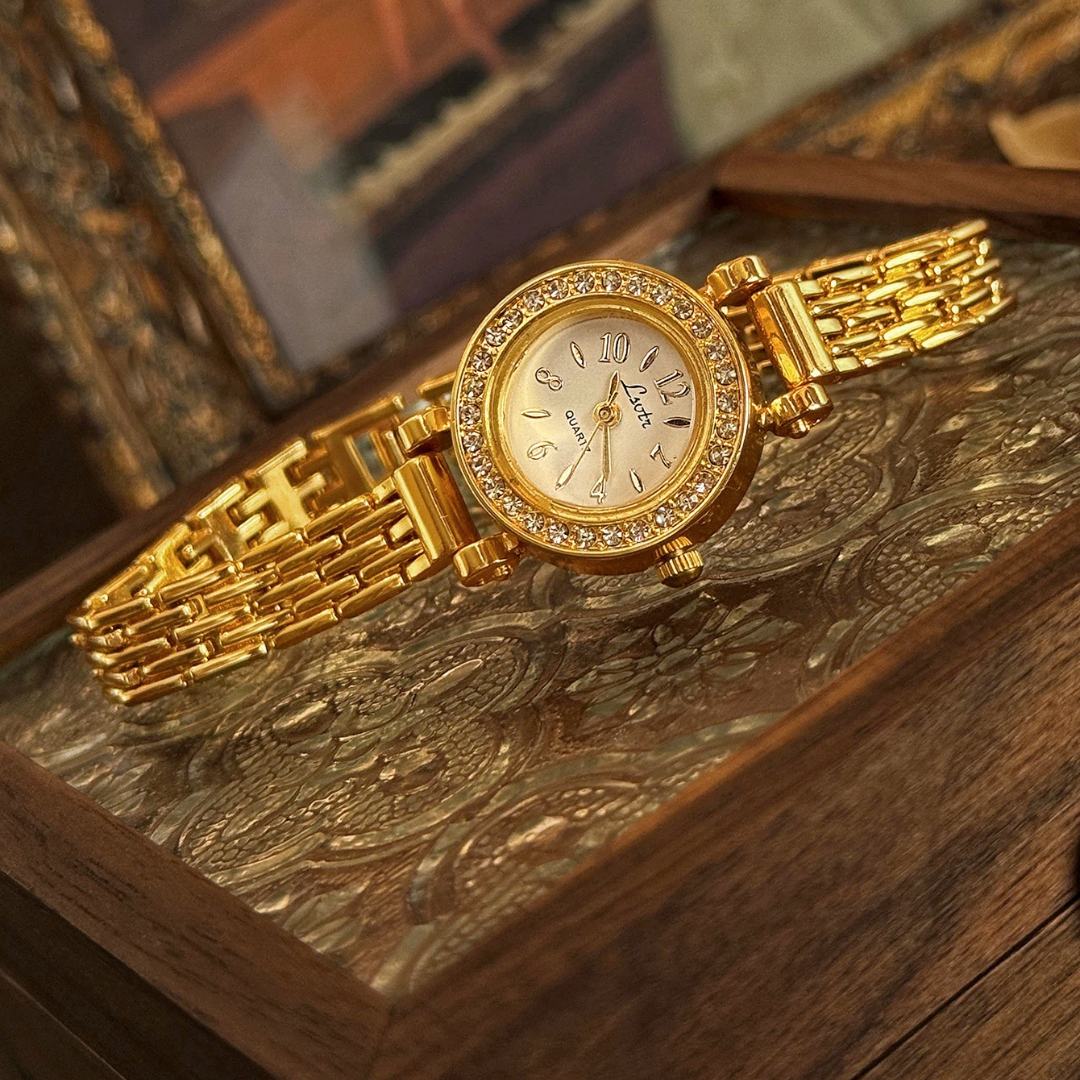 Gold wristwatch with gemstone accents on a wooden surface