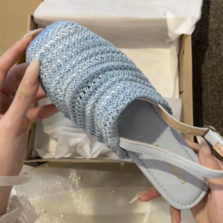 Blue glittery sandal held by a hand with a box in the background