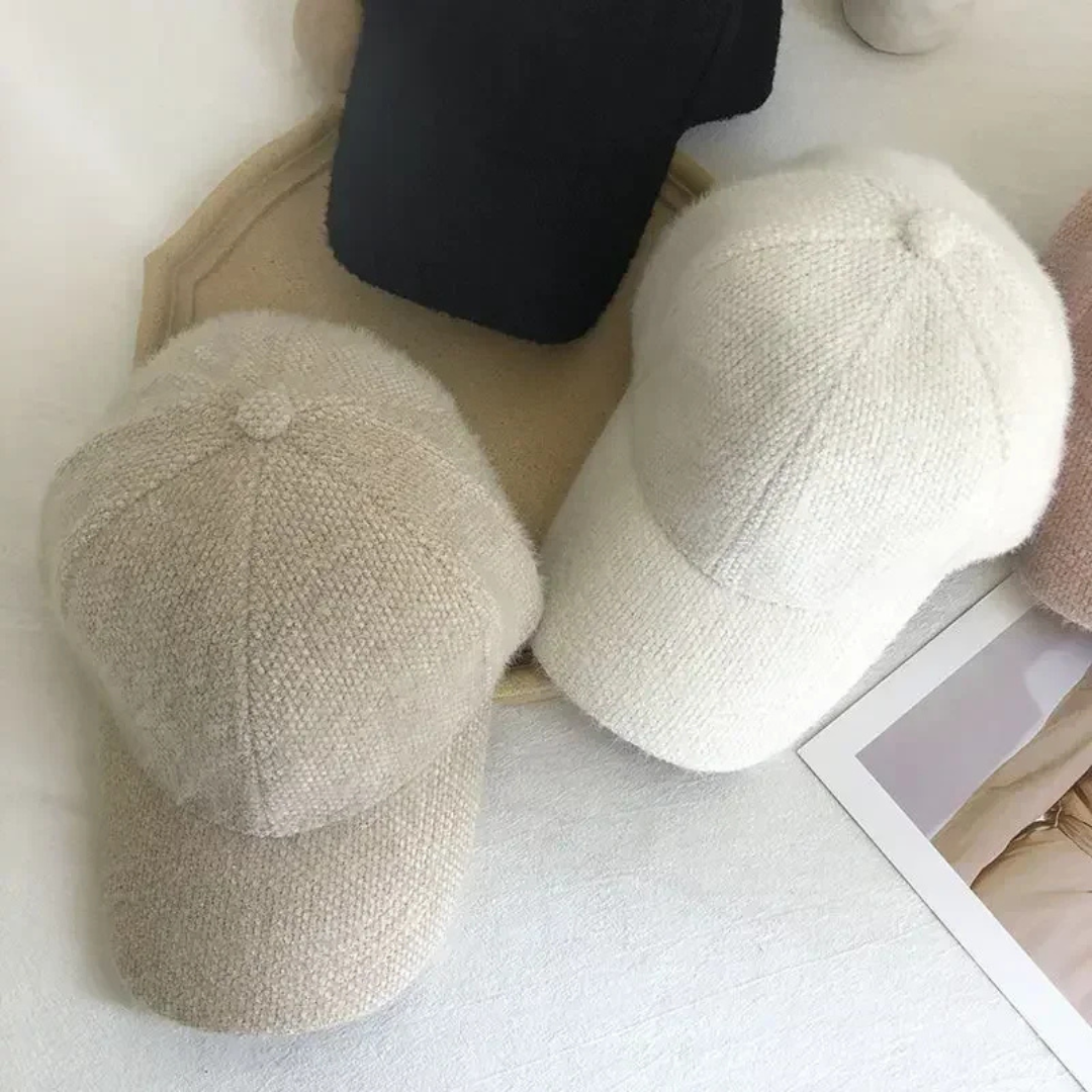 Two beige textured hats on a light surface with a blurred background