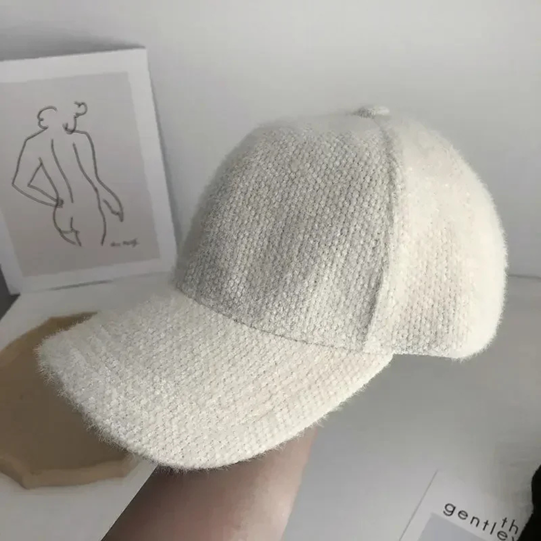White textured baseball cap held by a hand with a minimal background