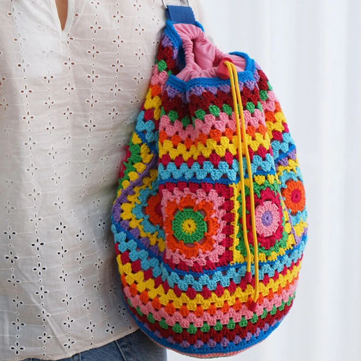 Colorful crocheted bag held by a person wearing a white blouse.