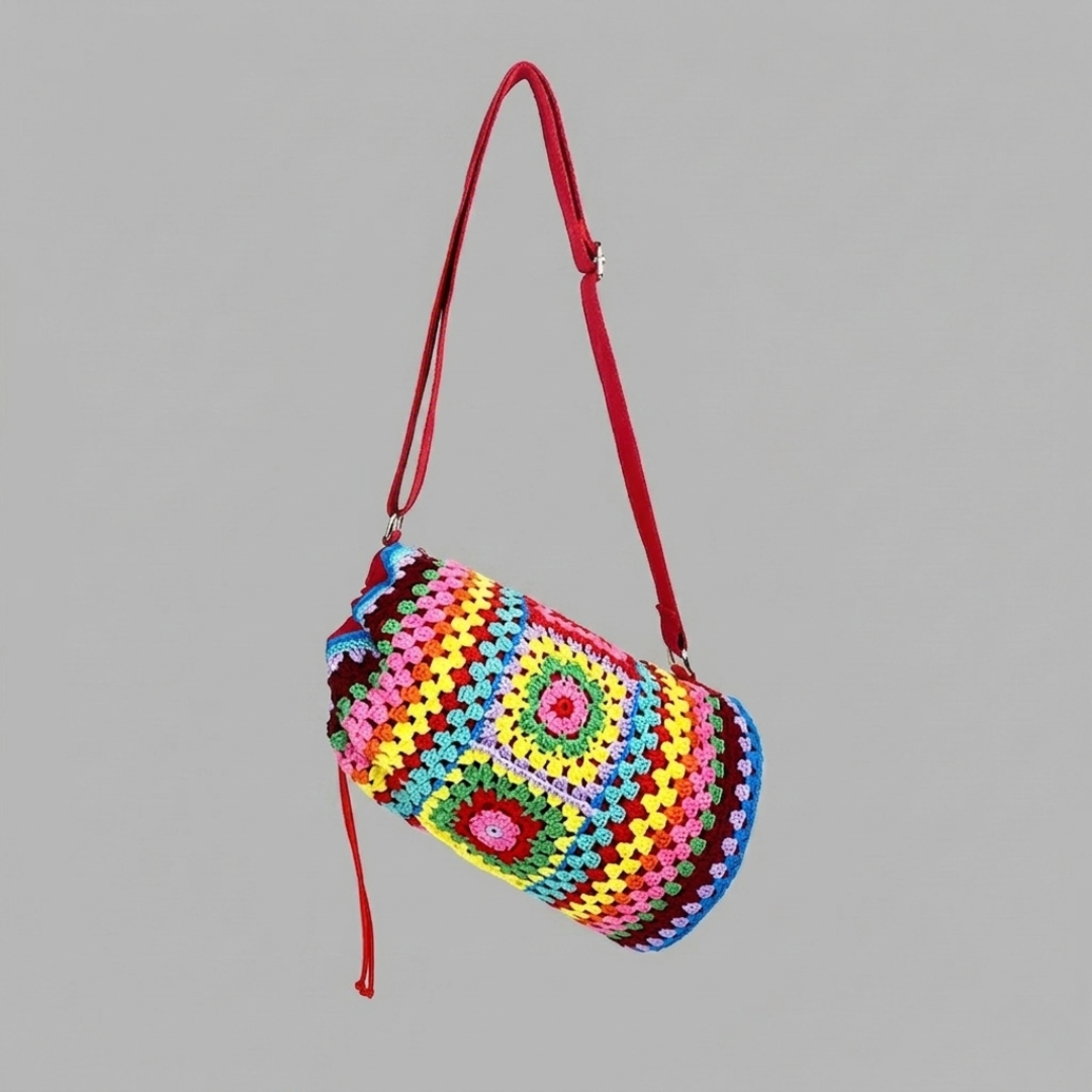 Colorful crocheted bag with a red strap on a gray background