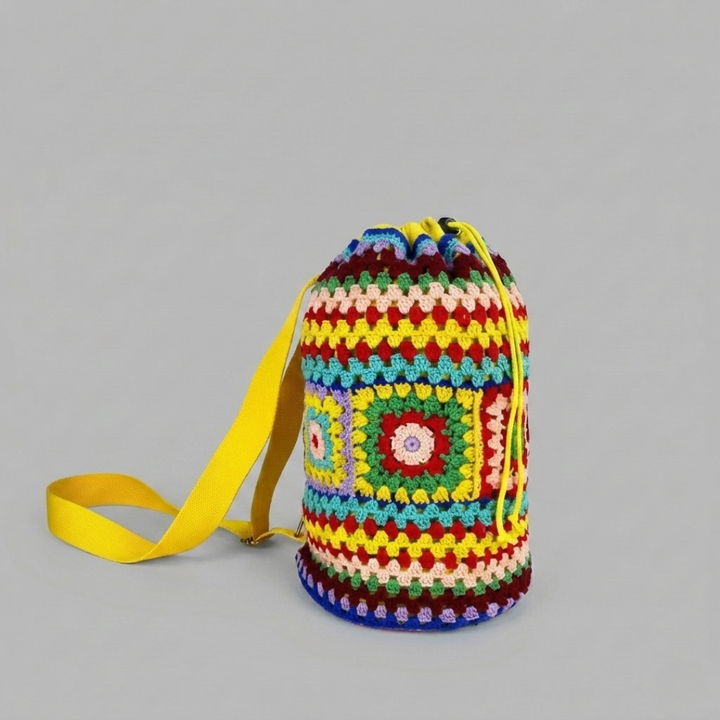 Colorful crocheted bag with a yellow strap on a gray background