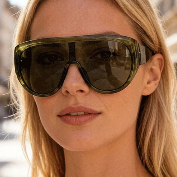 Close-up of a person wearing large green sunglasses with a blurred background