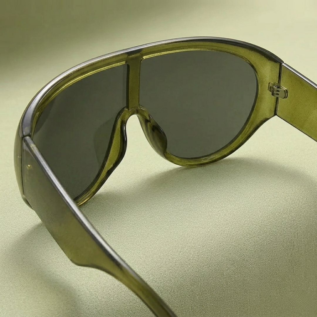 Sunglasses with a green frame and dark lenses on a light green background