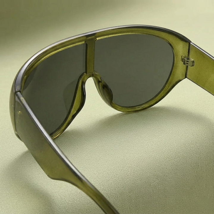 Sunglasses with a green frame and dark lenses on a light green background