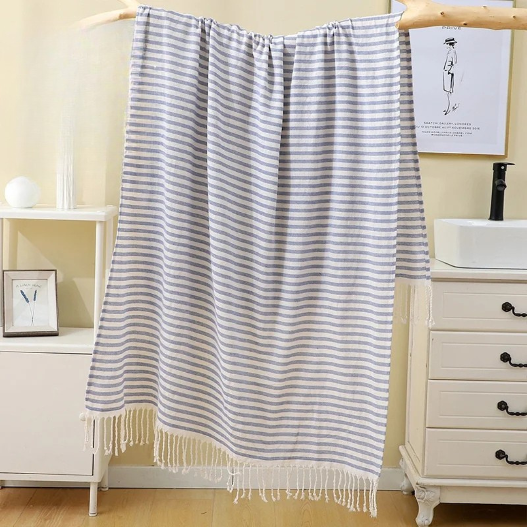 Blue Striped towel hanging on a wooden rod in a bathroom setting.