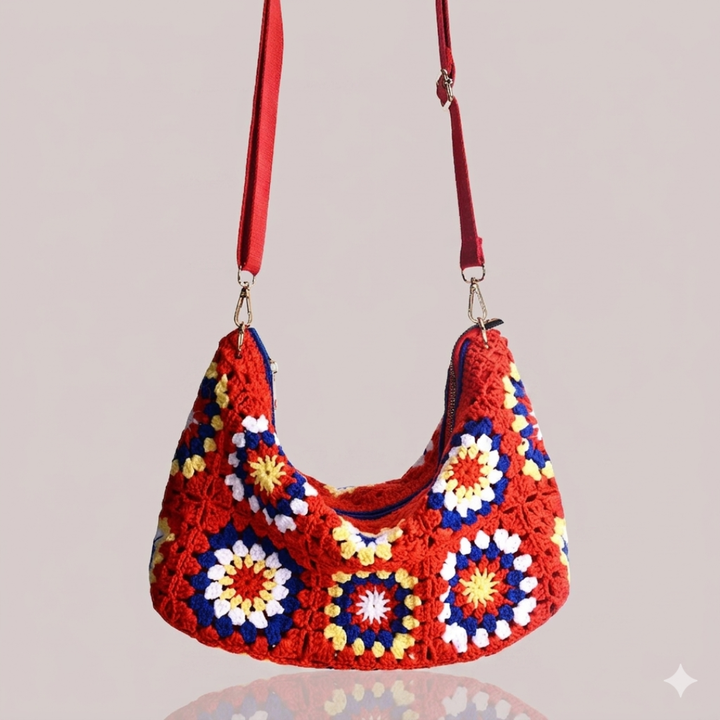 Colorful crocheted handbag with red strap on a light gray background