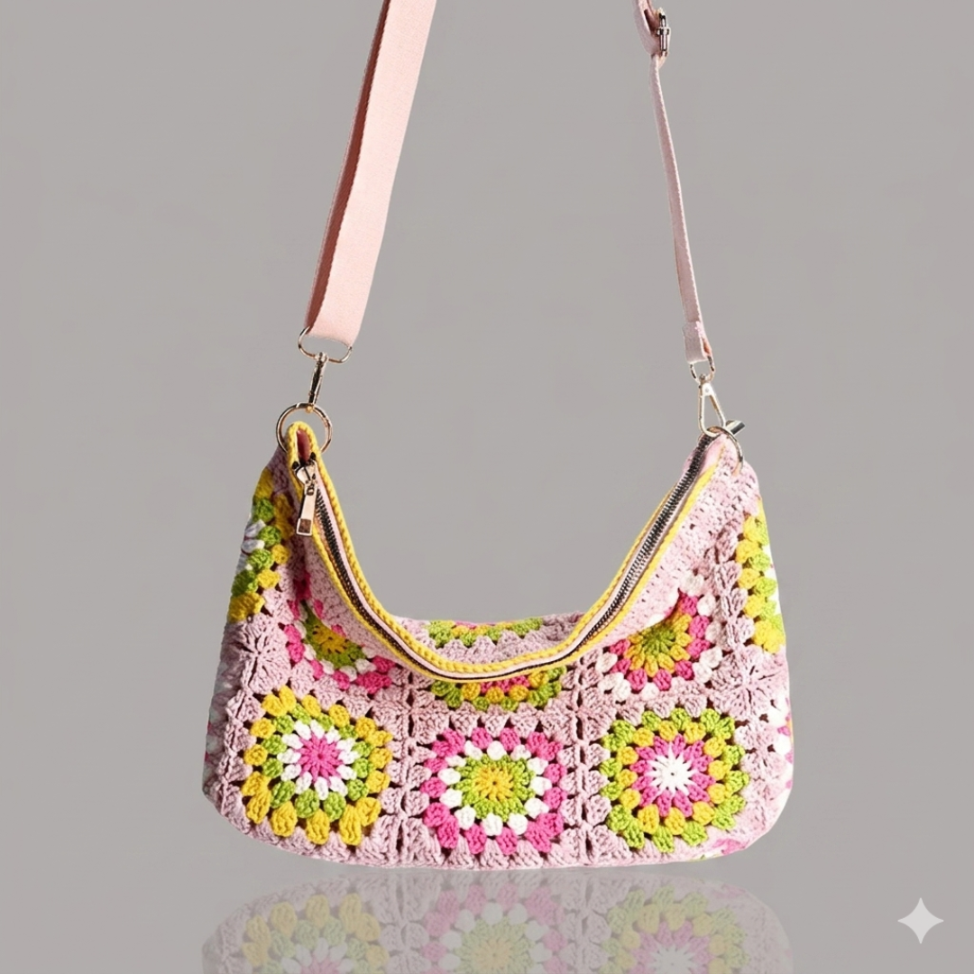 Colorful crocheted handbag with a pink strap on a gray background