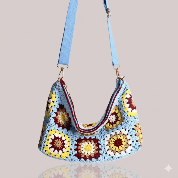 Colorful crocheted bag with a blue strap on a beige background