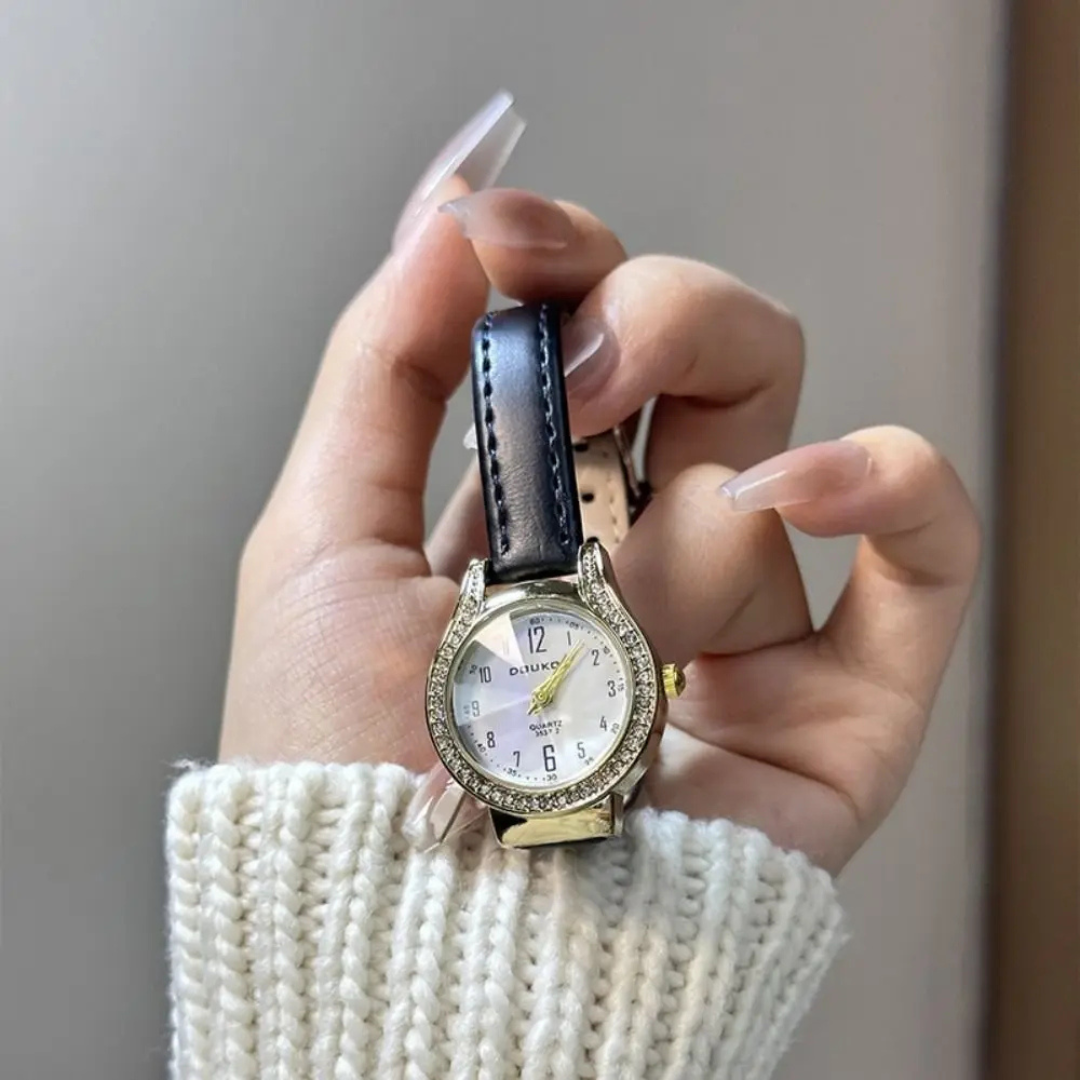 Hand holding a watch with a blurred background