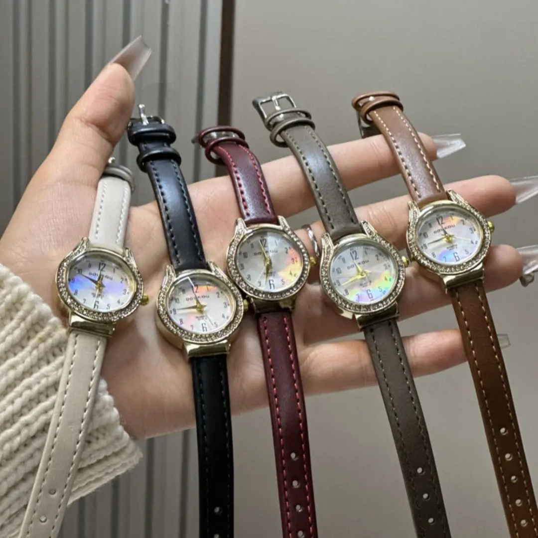Five watches with different leather straps held in a hand against a neutral background