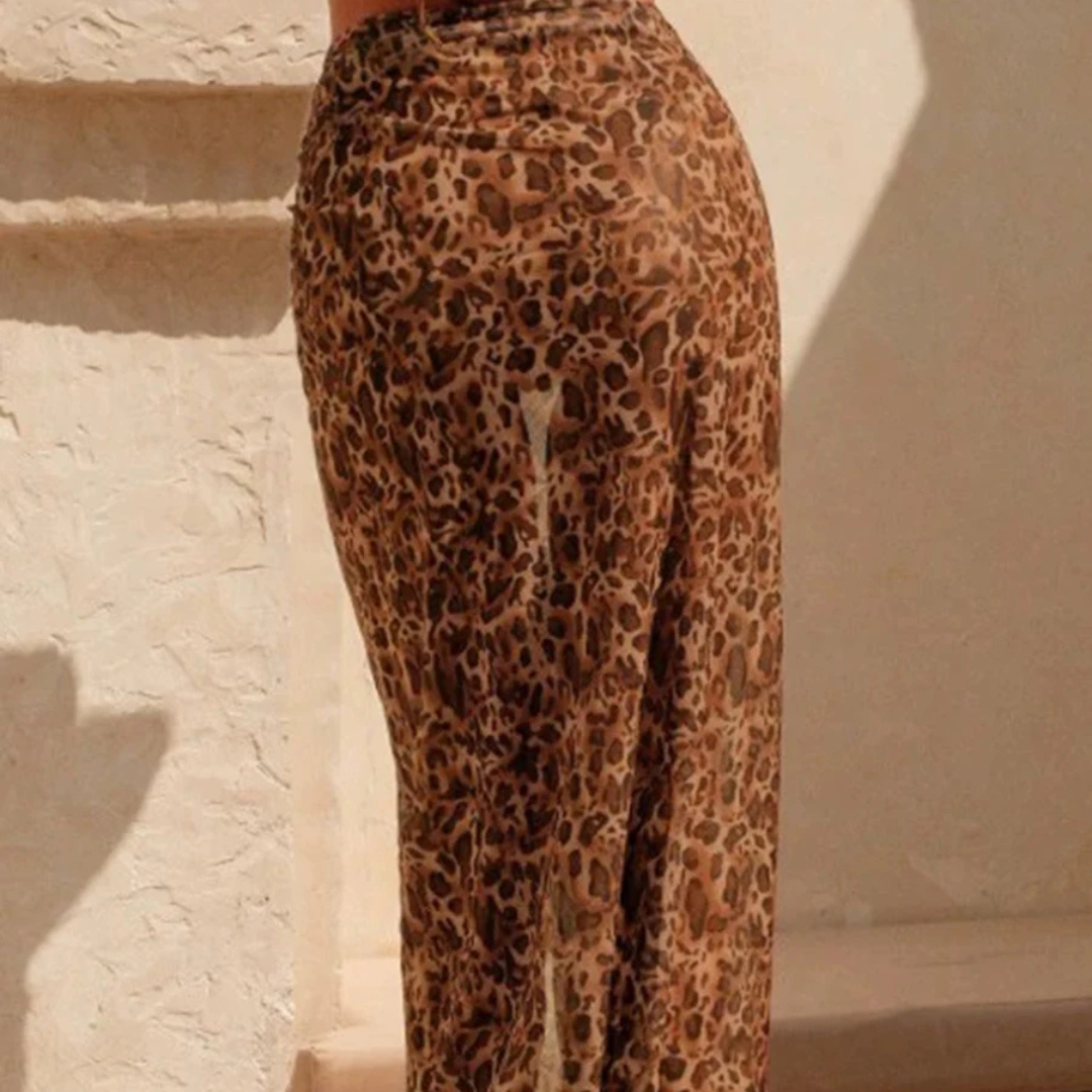 Leopard print pants worn by a person against a beige wall.