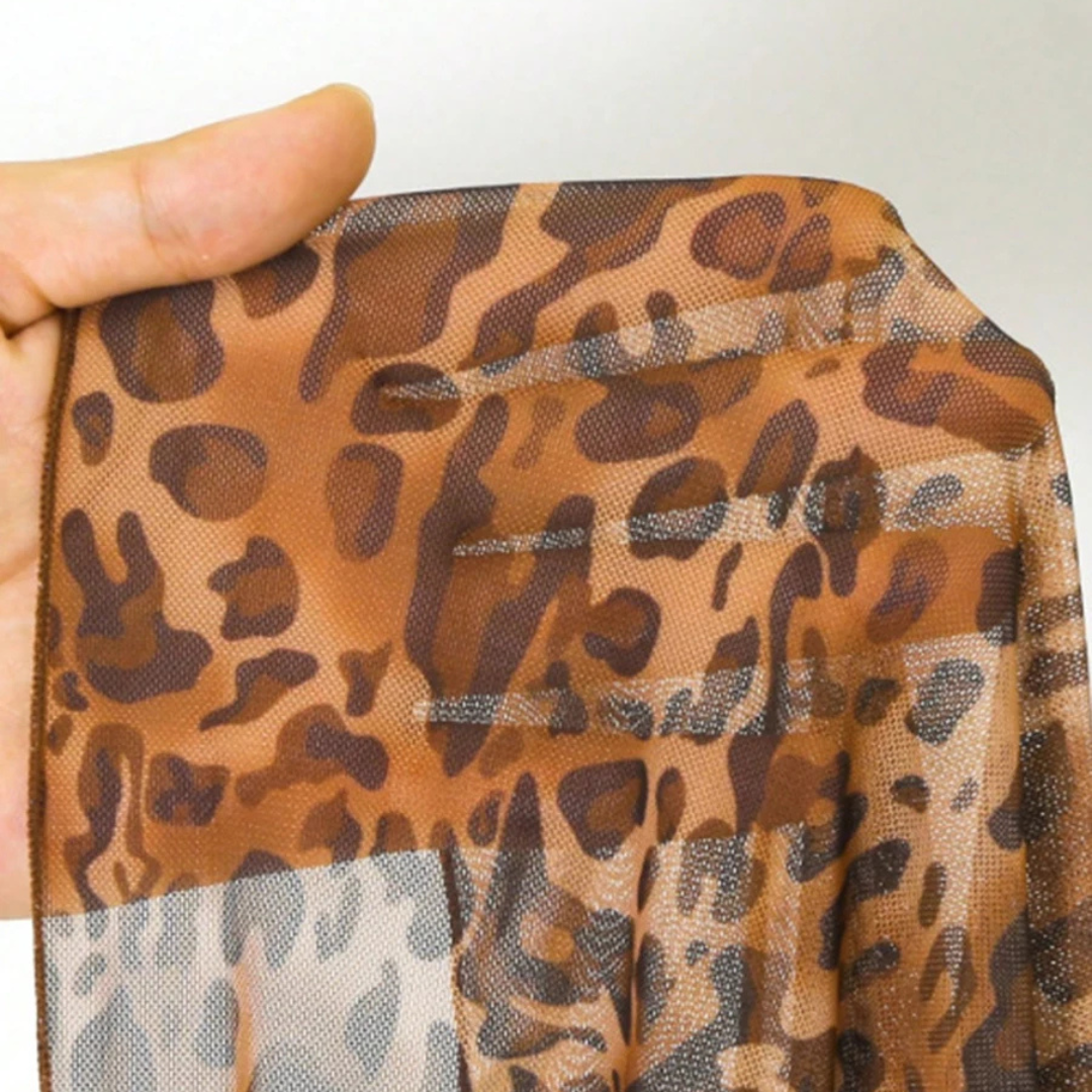Hand holding a leopard print fabric with a plain background