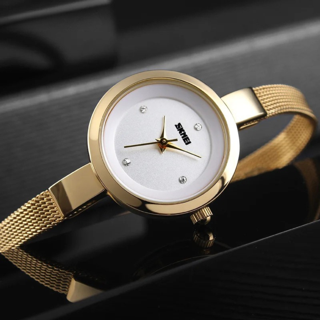 Gold wristwatch with a white face on a reflective black surface