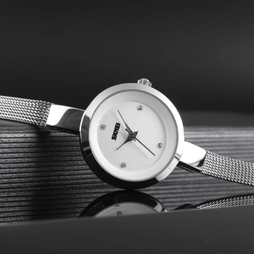 Silver watch with a white face on a reflective surface