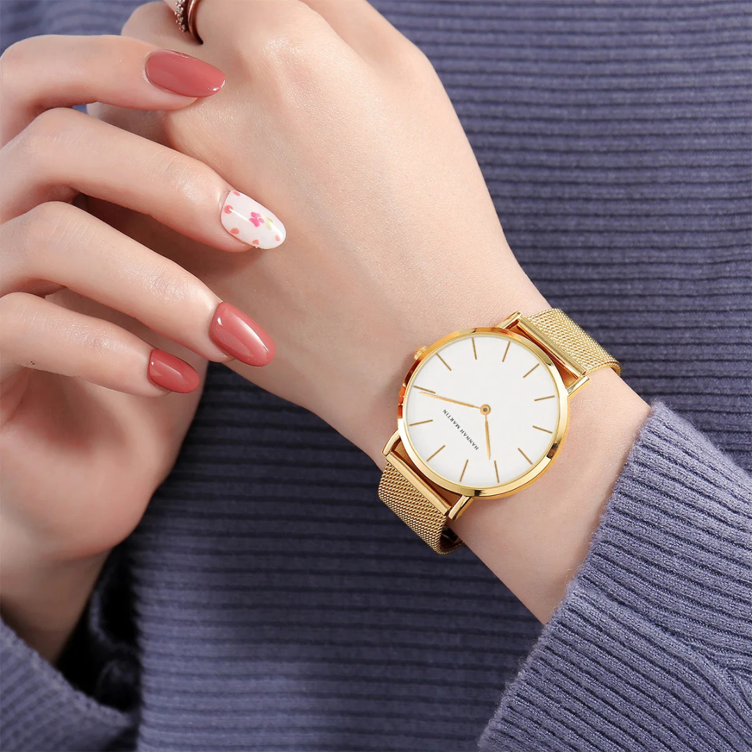 Gold wristwatch on a person's wrist with a light background