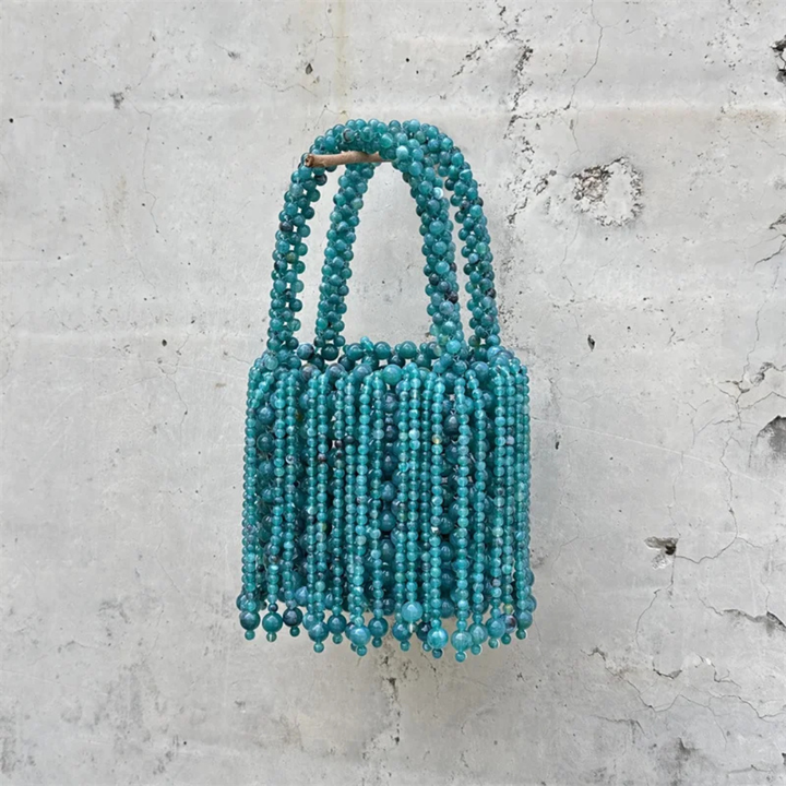 Blue beaded handbag on a textured gray background