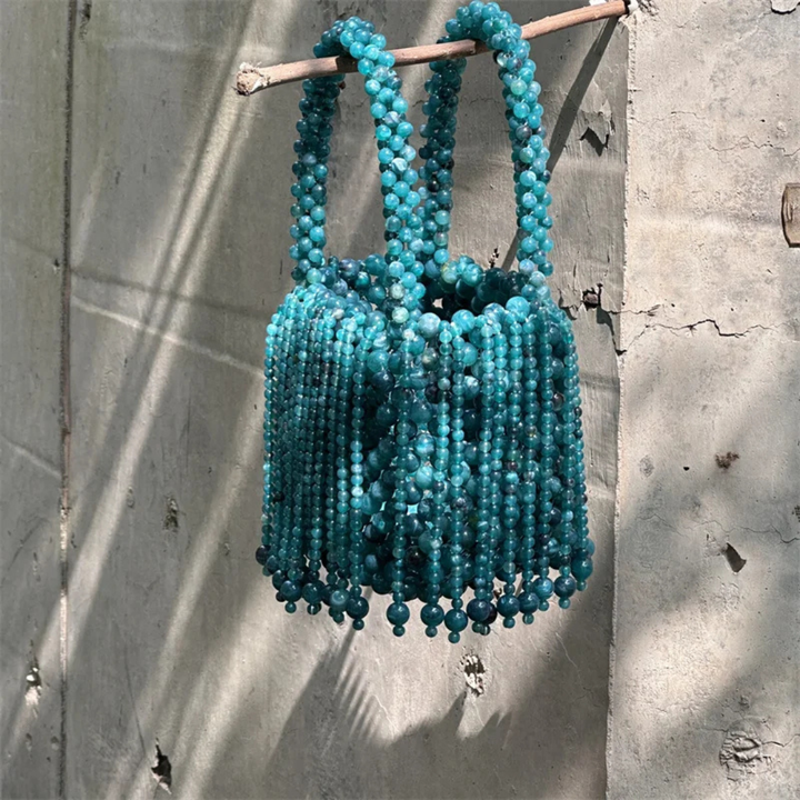 Blue beaded handbag hanging against a concrete wall