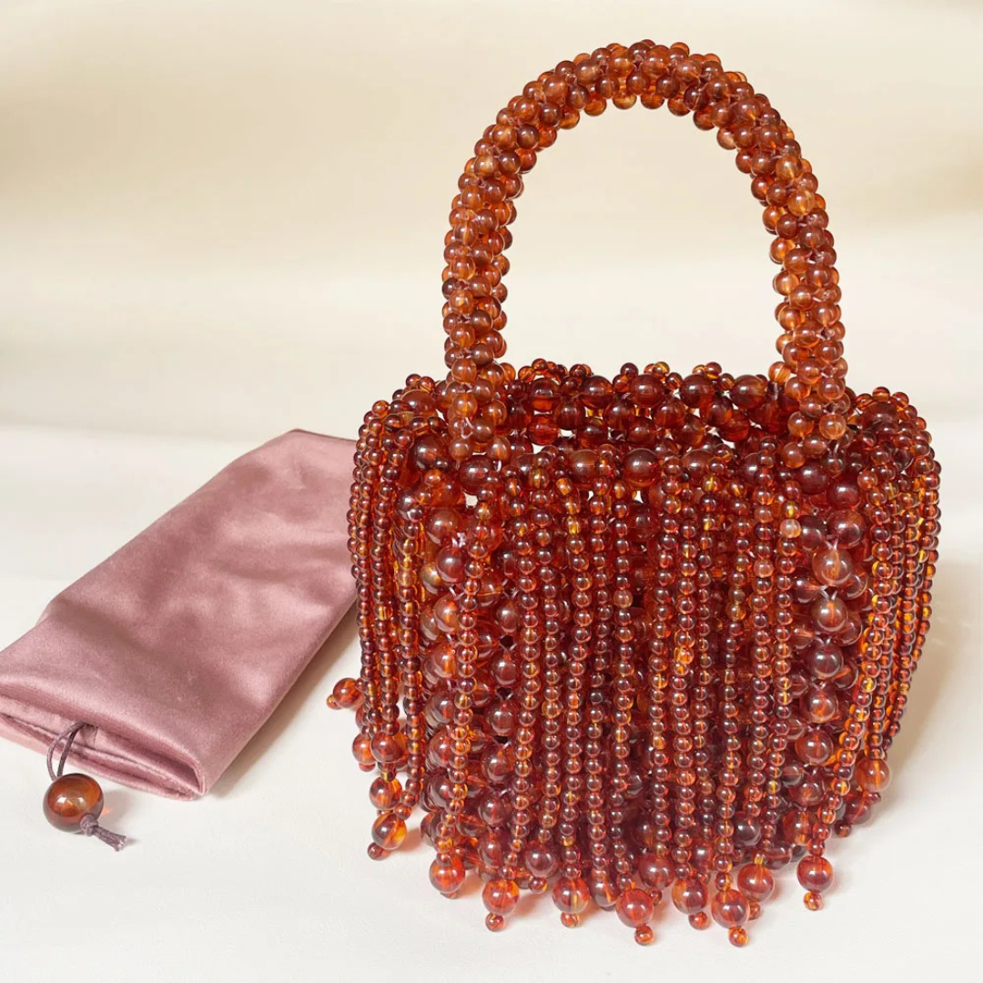 Brown beaded handbag with a pink satin bag on a light background