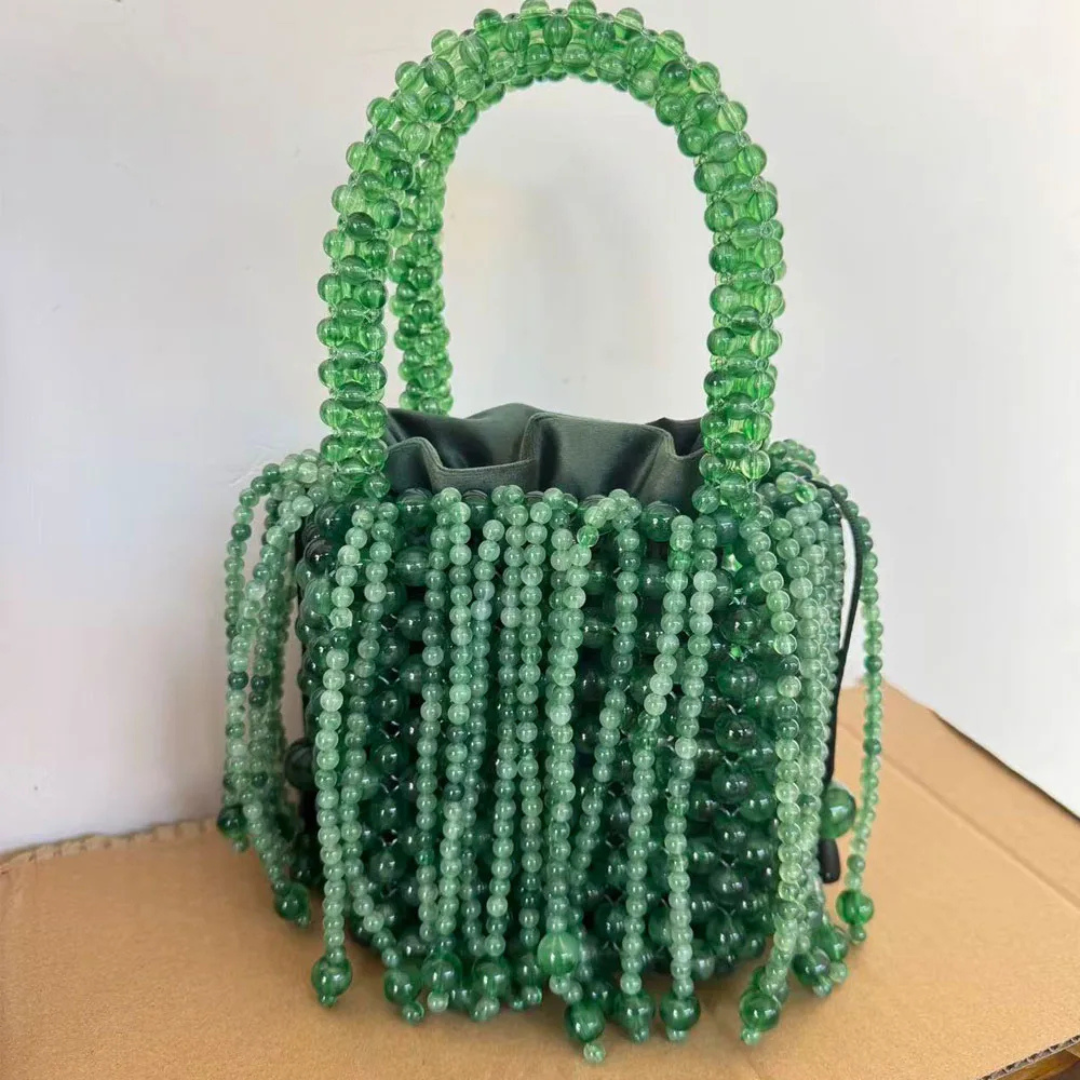 Green beaded handbag on a beige surface with a white background