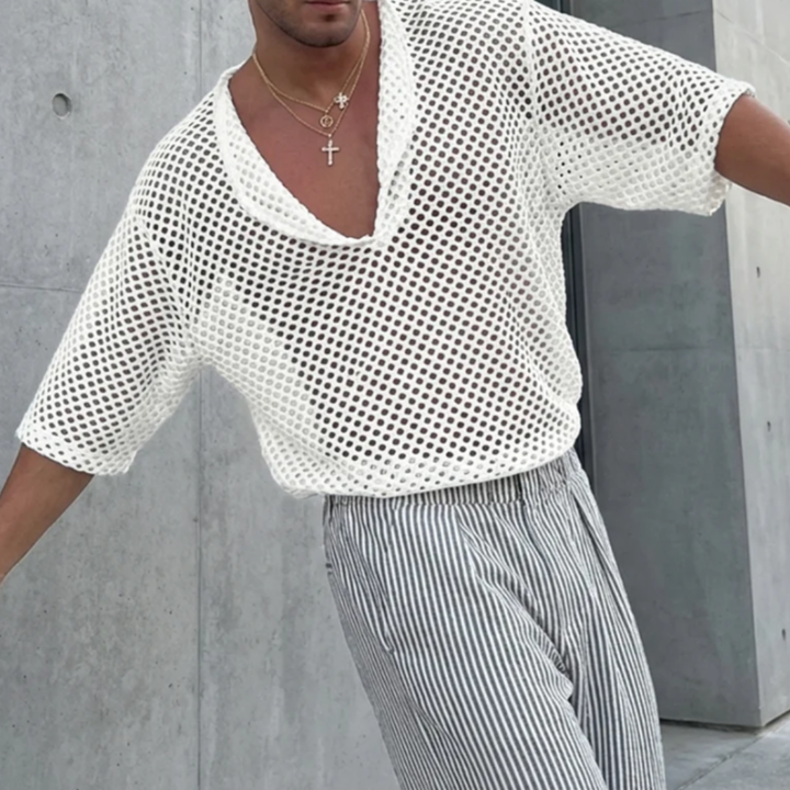 Person wearing a white mesh top and striped pants against a concrete wall.