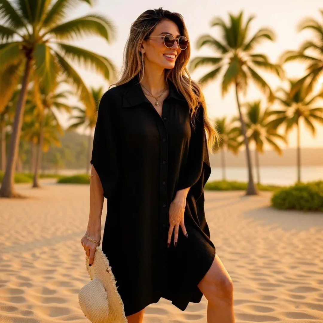 Woman in a black dress standing on a beach with palm trees in the background