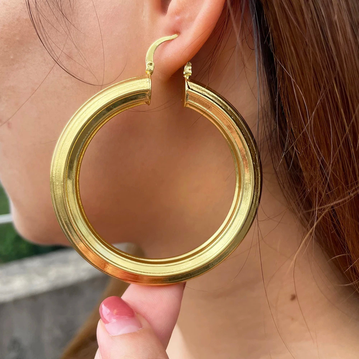 Gold hoop earring worn by a person with blurred background