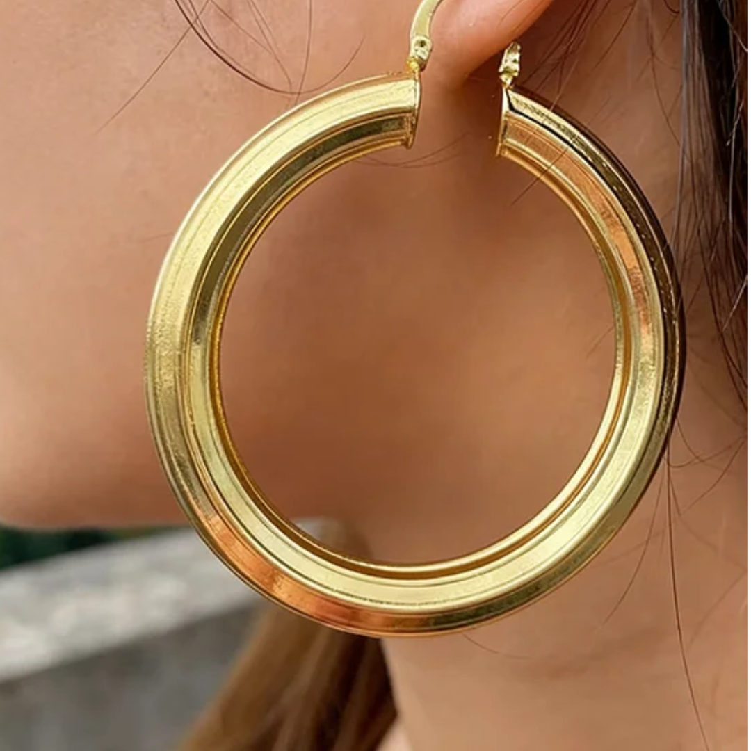 Gold hoop earring worn by a person with a blurred background