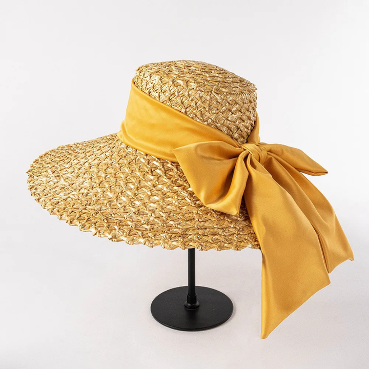 Woven straw hat with a large yellow bow on a white background