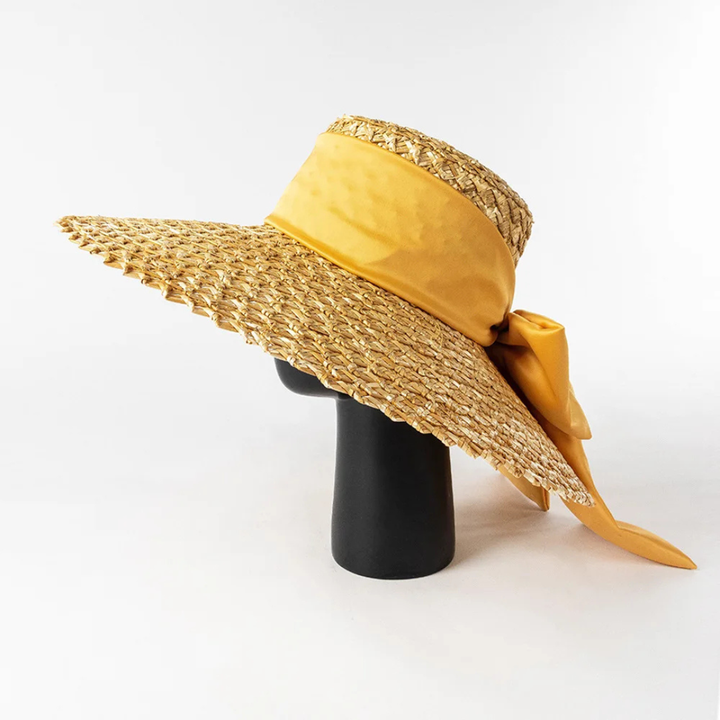Wide-brimmed straw hat with a yellow ribbon on a white background