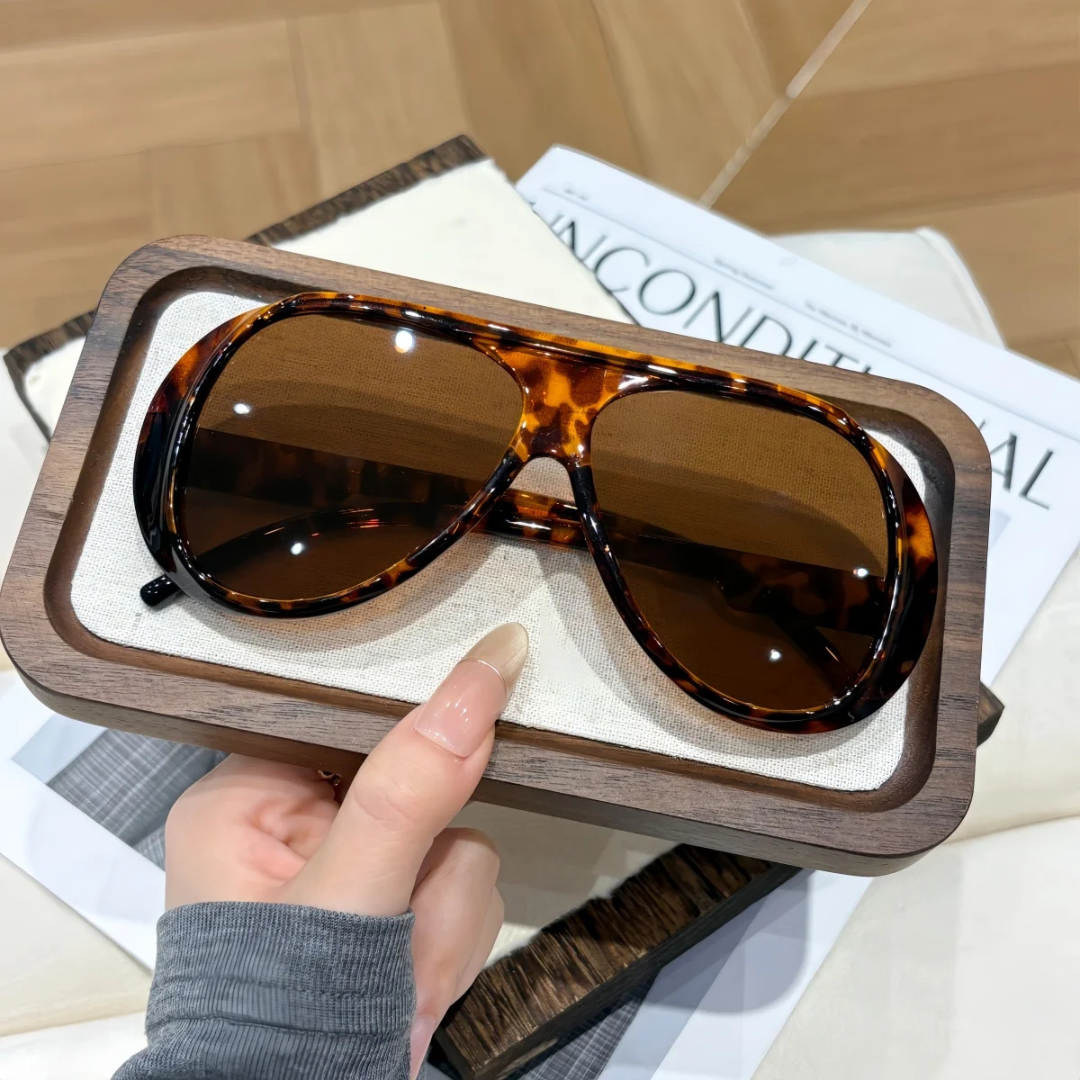 Hawksbill Turtle sunglasses with wooden frame held by a hand on top of a magazine