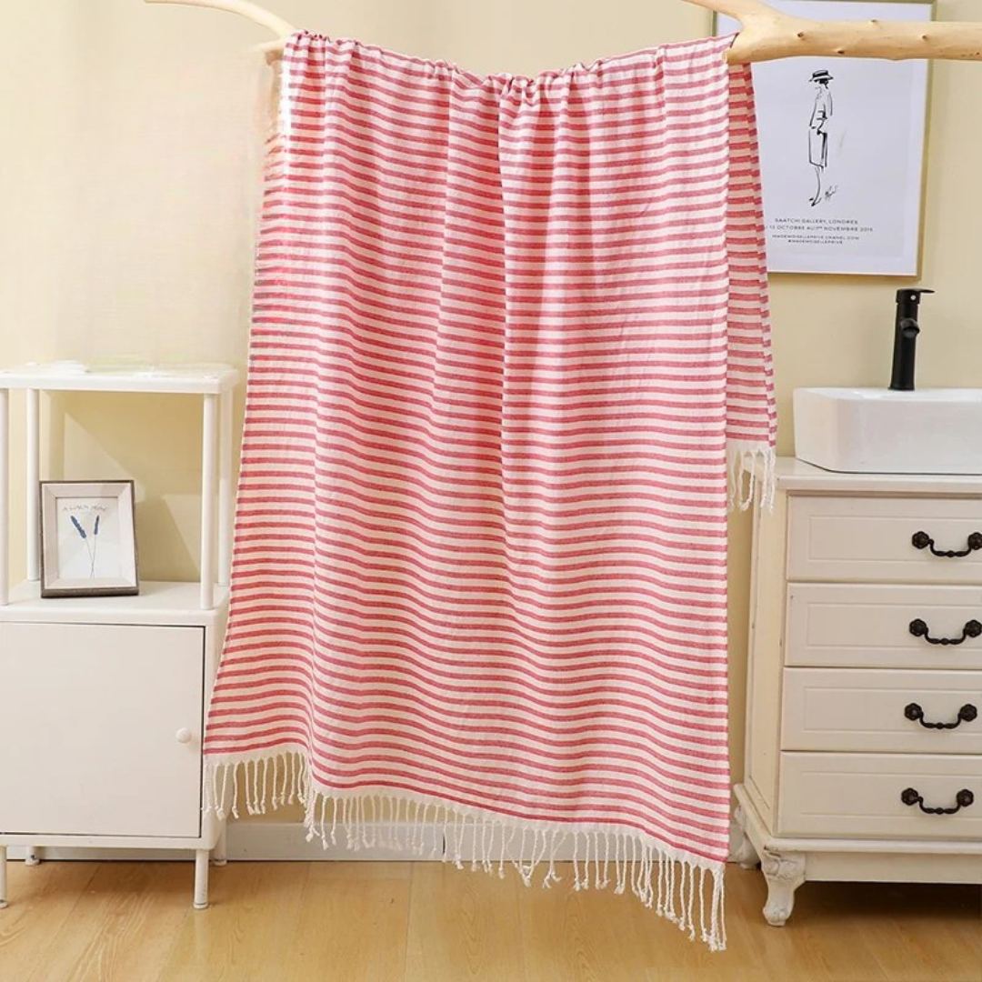 Striped pink towel hanging in a bathroom with a sink and cabinet.
