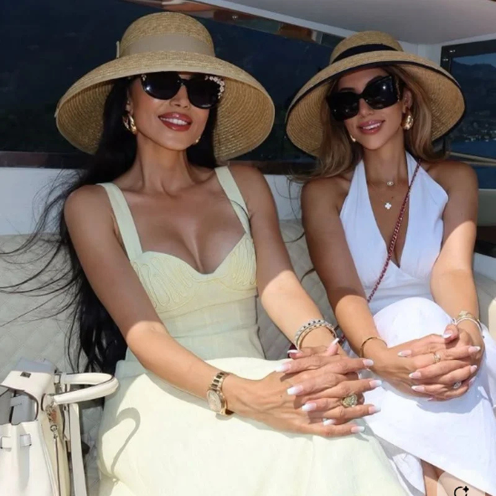 Two women sitting on a boat, wearing sun hats and sunglasses.