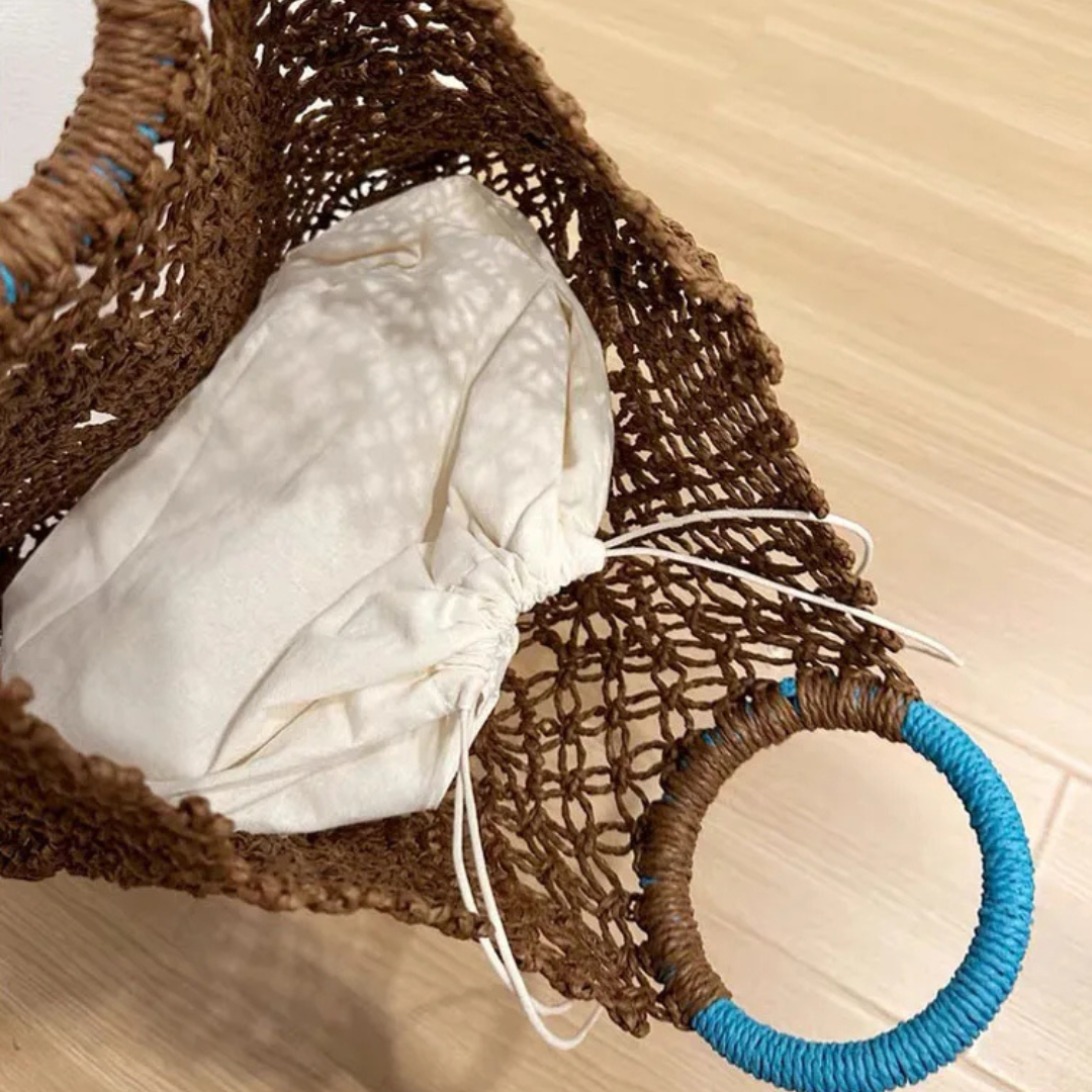 Brown woven basket with a white cloth and blue ring on a light wooden surface