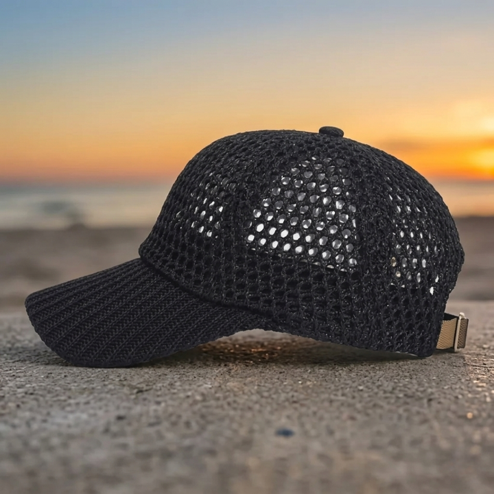 Black mesh cap on a textured surface with a sunset in the background