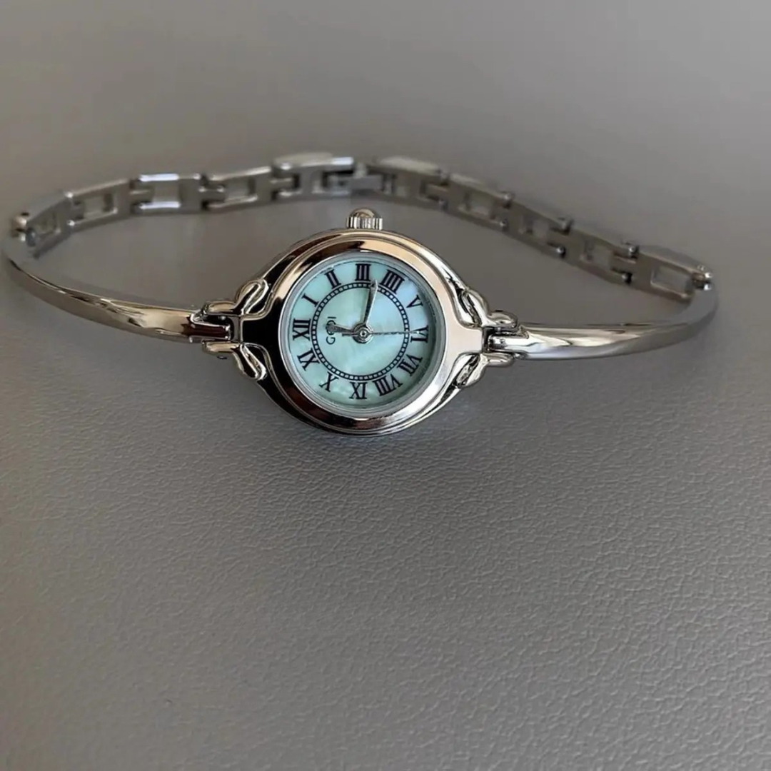 Silver bracelet with a watch face on a gray background