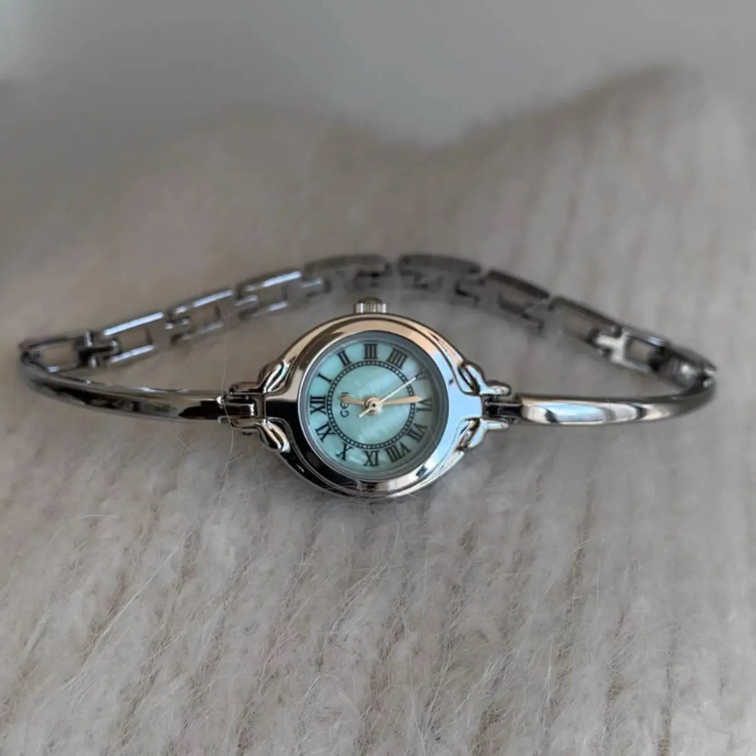 Silver bracelet watch with a light blue face on a beige surface