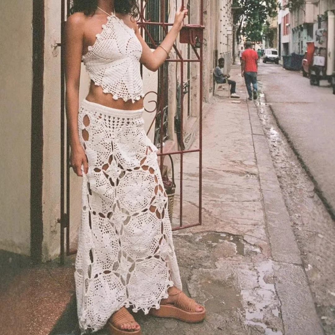 Woman wearing a crochet top and skirt with a beige clutch against a neutral background