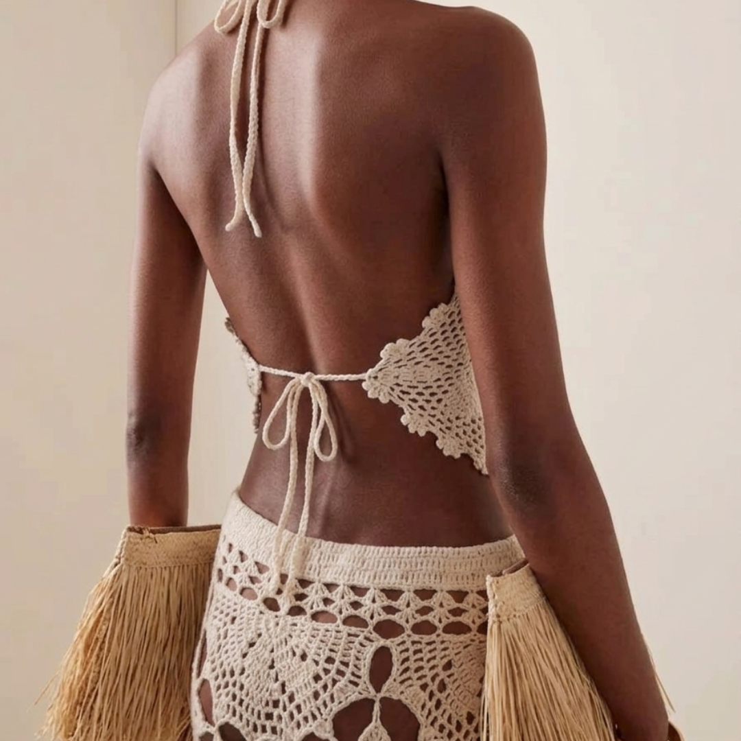 Woman wearing a crochet top and skirt with a beige clutch against a neutral background