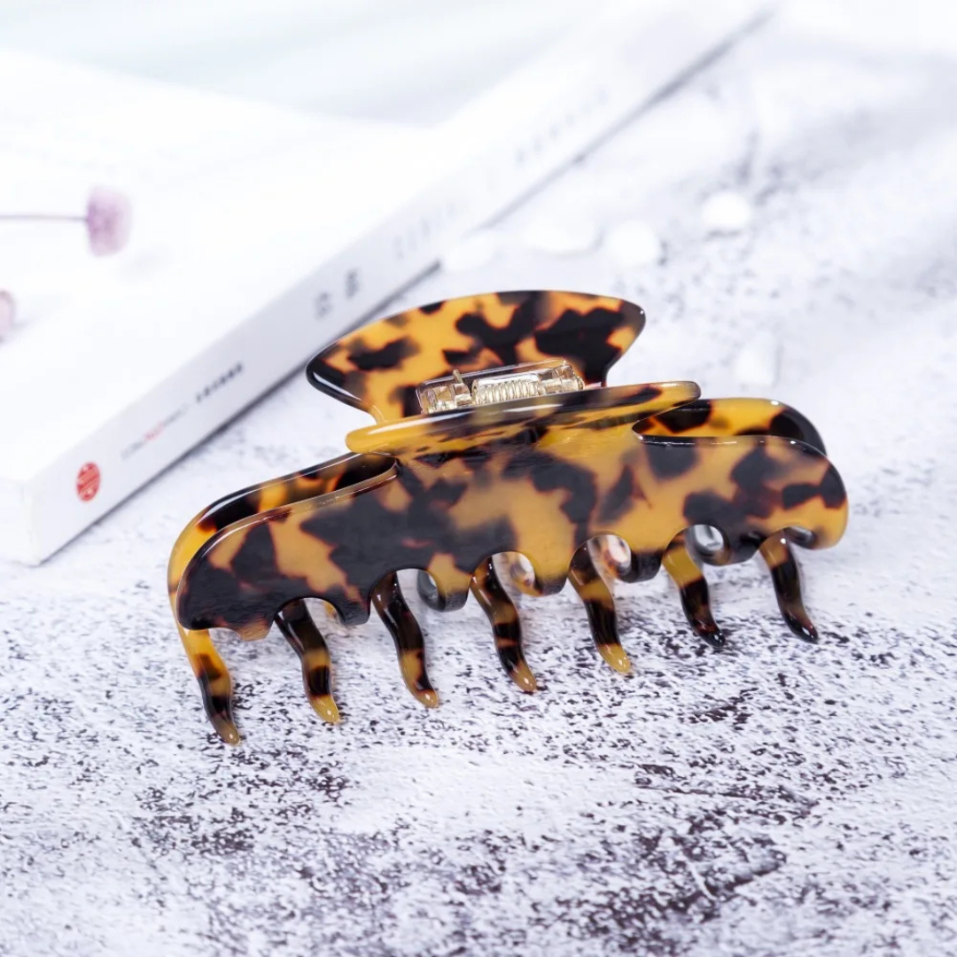 Dark hair clip on a textured surface with a blurred background
